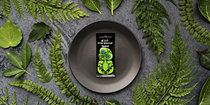 Tiki Magnet on black plate surrounded by green leaves